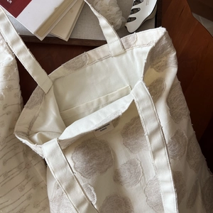 Close-up of white cotton linen tote bag featuring textured floral flocking and inner pocket