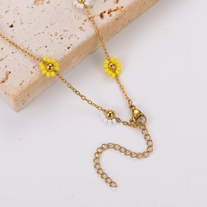 Elegant gold necklace and bracelet set featuring yellow and white daisy flowers on stone