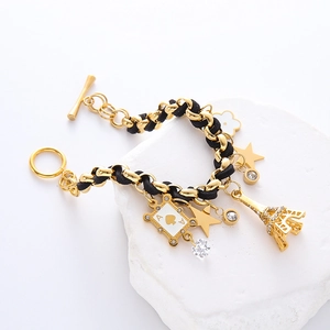 Gold chain bracelet with Eiffel Tower and poker charms on a stone pedestal