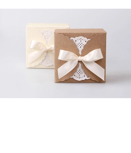 Detail of square paper gift boxes with lace pattern and elegant ribbon bow decoration