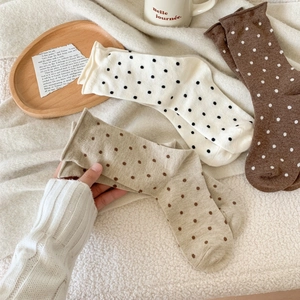 Close-up of retro polka dot wool crew socks in beige and khaki on a cozy tray
