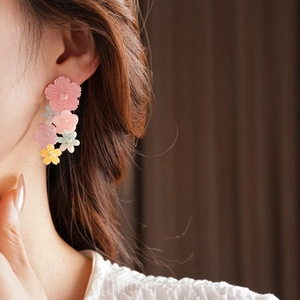 Close-up of colorful resin flower dangle earrings worn by a model for a beach style look