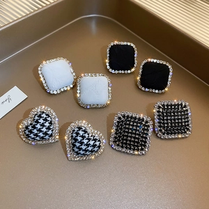 Detailed view of vintage houndstooth heart earrings and rhinestone studs on a tray