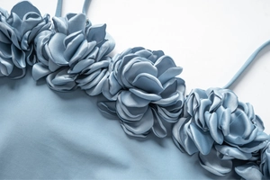 Détail de maillot de bain bleu clair avec fleurs 3D faites main sur l'encolure