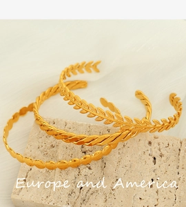 Detail of three vintage gold cuffs with wheat ear and twisted rope textures on stone