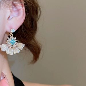 Close-up of sparkling floral fan-shaped crystal earrings on ear with champagne gold finish