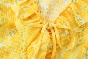 Detail of yellow floral seersucker fabric featuring a delicate tie-bow knot closure