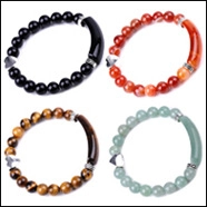 Detail of beaded yoga bracelets with heart pendants, tiger eye stones and metal tubes