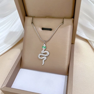 Silver snake pendant necklace with green eyes and white zircon in a golden jewelry box
