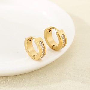 Détail de boucles d'oreilles en acier doré ornées de zircons carrés transparents