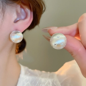 Macro detail of round 18k gold plated earrings with brushed texture and star accents
