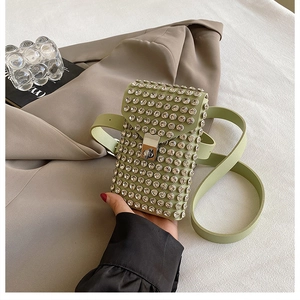 Close-up of light green rhinestone crossbody bag with silver twist lock on beige blazer