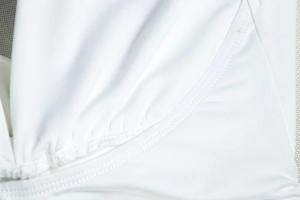 Detailed close-up of white high-elastic knit fabric showing seams and gathered texture
