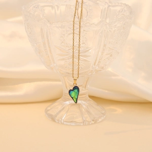 Elegant gold chain necklace with a gradient heart pendant on a romantic silk background