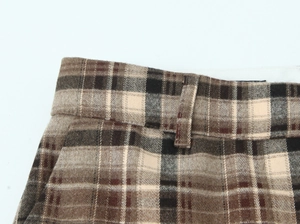 Gros plan détaillé du pantalon à carreaux marron montrant la taille et la texture du tissu