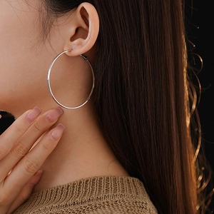Close-up of silver-plated hoop earring with textured matte finish worn by a model