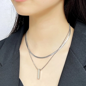 Close-up of double layered silver snake chain with geometric pendant on black blazer
