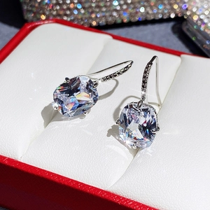 Macro shot of cushion-cut zircon earrings with claw setting in a luxury jewelry box
