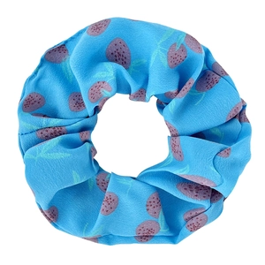 Detail of blue oversized fabric scrunchie featuring vibrant purple strawberry patterns