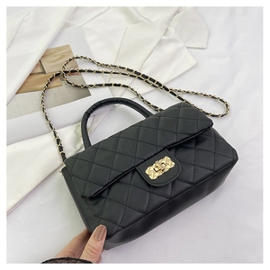 Detail of black quilted crossbody bag with golden chain strap and metallic lock closure