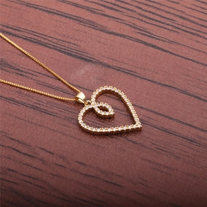 Detail of gold heart pendant necklace featuring micro-set zircons on a box chain