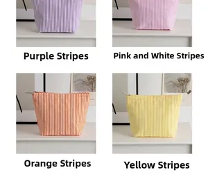Detail view of four striped seersucker makeup bags with metal zippers in a neat grid