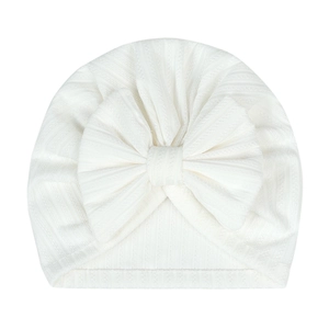 Detail of white newborn baby turban hat featuring a soft ribbed knit and a large bow