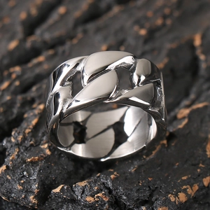 Macro shot of polished silver Cuban link ring for men on a dark wood background