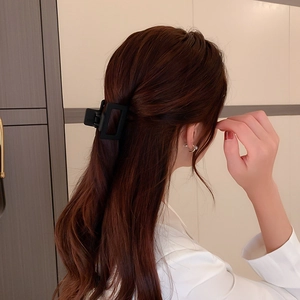 Détail d'une pince à cheveux rectangulaire noire mate portée par un mannequin