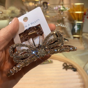 Detailed view of rhinestone bow hair claw clip with champagne crystals in hand