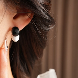 Close-up of black and white oval geometric stud earrings with a glossy finish