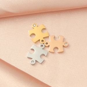 Detail of puzzle-shaped charms in gold, silver, and rose gold with crystal inlay on pink silk