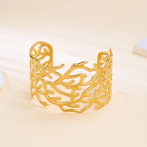 Detailed close-up of golden coral texture on a stainless steel open cuff bracelet