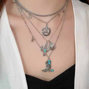 Close-up of layered silver necklace with western cowboy hat, boot, and cactus pendants