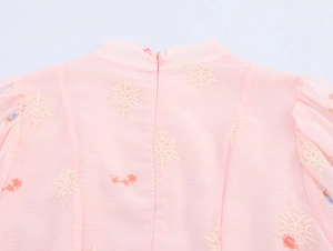 Detail van roze chiffon jurk met ritssluiting achteraan en bloemenborduursels