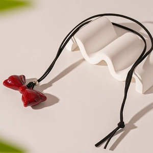 Detail of red resin bow pendant necklace with black cord and silver adjustment bead