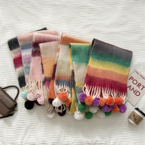 Detailed flat lay of rainbow striped mohair scarves with soft pompom tassel ends