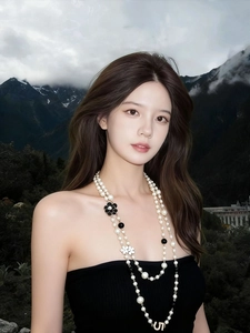 Detail of double-layer pearl necklace with camellia charms worn on a black dress