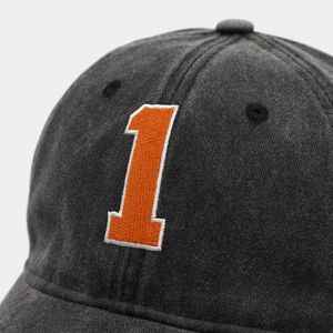 Close-up of orange 3D embroidered number 1 on washed charcoal grey baseball cap