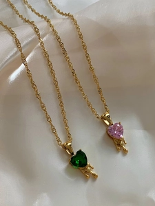 Golden chain necklaces with melting green and pink heart pendants on silk fabric