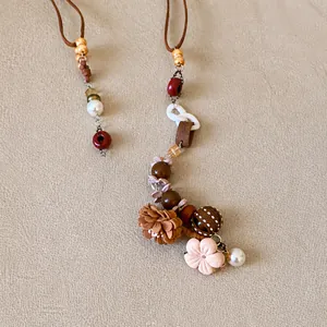 Détail d'un collier bohème vintage avec fleurs en tissu, perles colorées et breloques