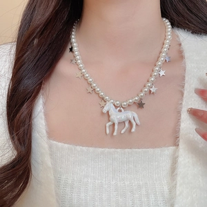 Détail d'un pendentif licorne blanche sur un collier de perles avec étoiles sur un mannequin