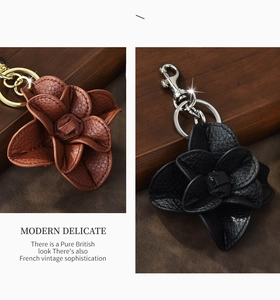 Detail of leather camellia flower keychains in brown and black with metal hardware
