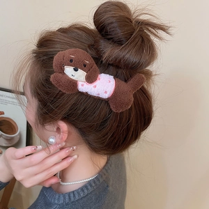 Detailed view of plush brown puppy hair clip with pink polka dot outfit on a bun