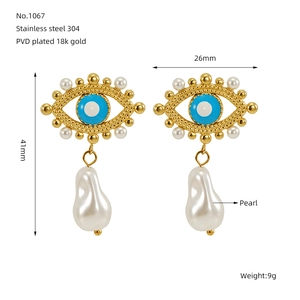 Detailed macro view of 18k gold PVD evil eye earrings with irregular pearl charms