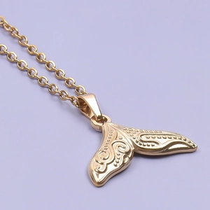 Detailed view of a golden stainless steel whale tail pendant on a purple background