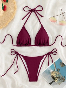 Flat lay of purple ribbed bikini set with sunglasses and beach straw hat on white fabric