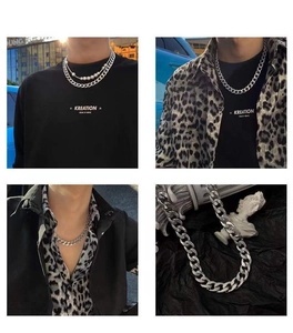 Detail of silver Cuban chain layered with pearl necklace on a model wearing a black t-shirt