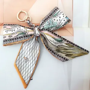 Detail of silk camellia bow keychain with Le Monde print and gold hardware