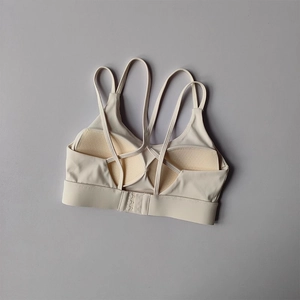 Detail of cross-back straps and breathable mesh lining on beige sports bra